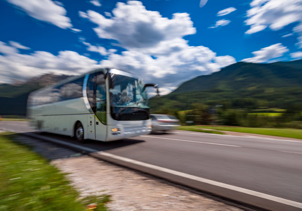 Tourist bus traveling on the road in the background the Dolomites Alps Italy. Warning - authentic shooting there is a motion blur.